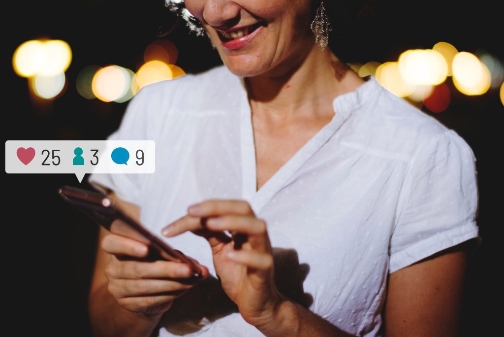 Happy adult woman using her smartphone at a dinner party